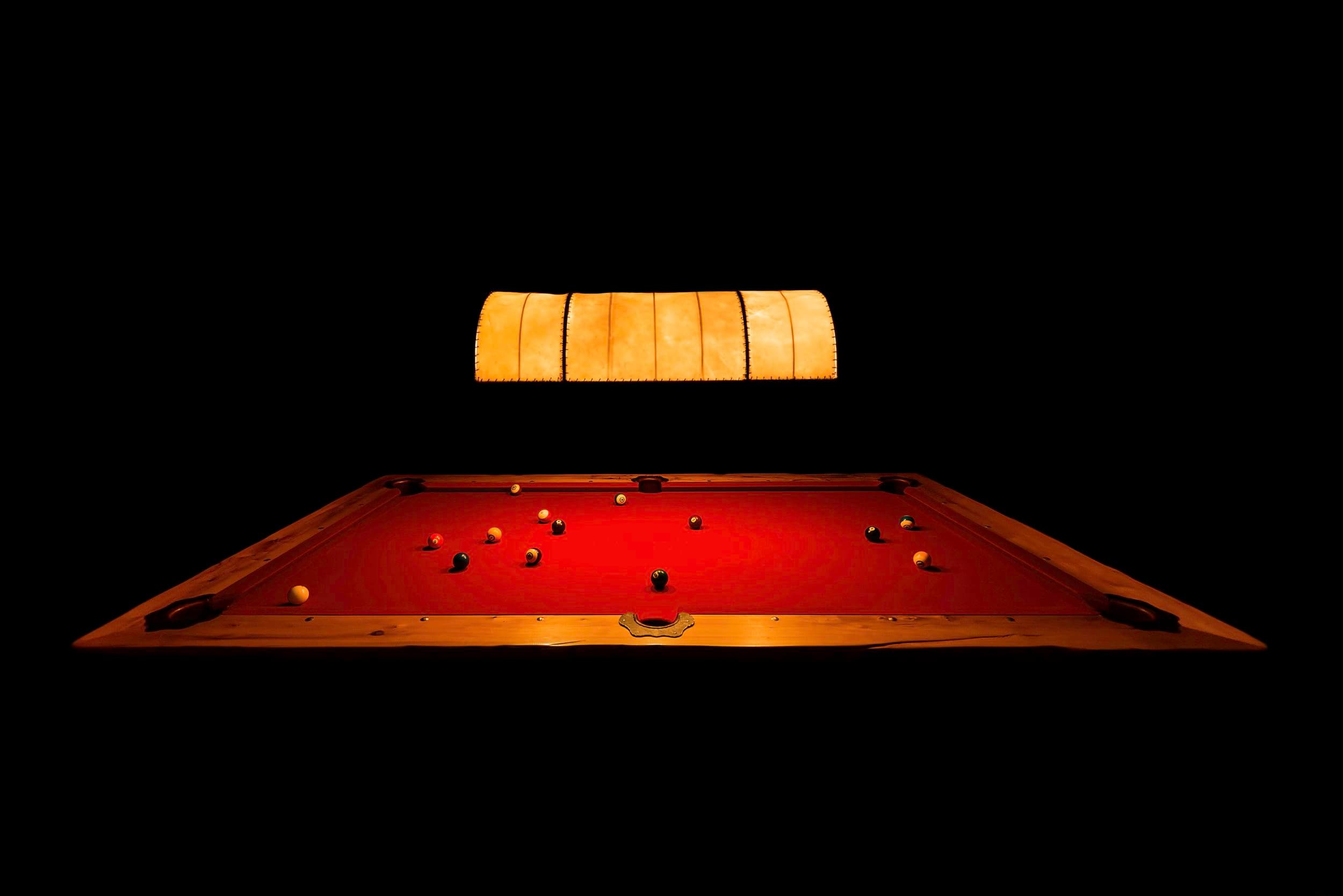 Pool table under a lamp in the dark